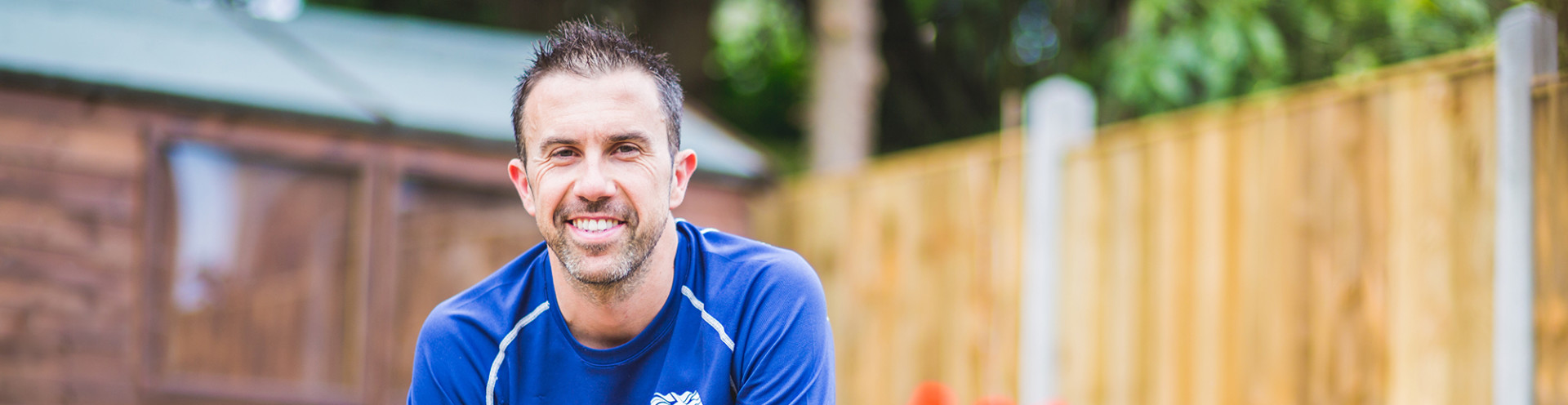 Andy Lewis smiling at the camera and sitting at the garden