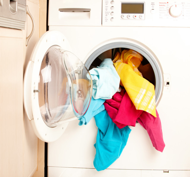 Close-up on a washing machine with clean colourful clothes.