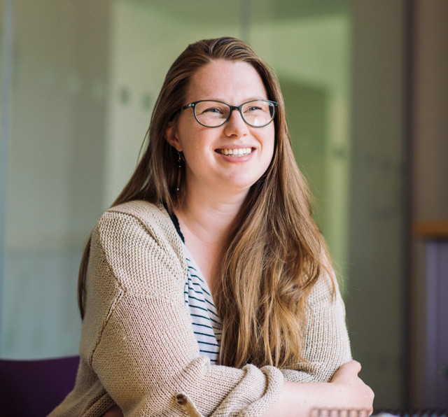 Team member Laura smiling at her desk.