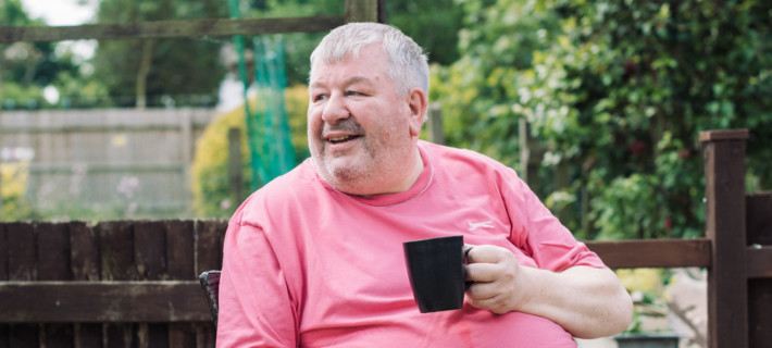 Eric holding his coffee mug in a garden.