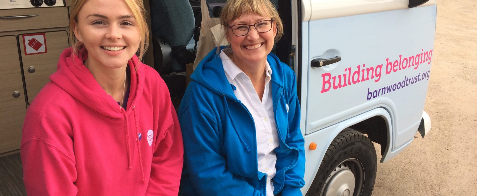 Team members smiling in front of the tour camper van.