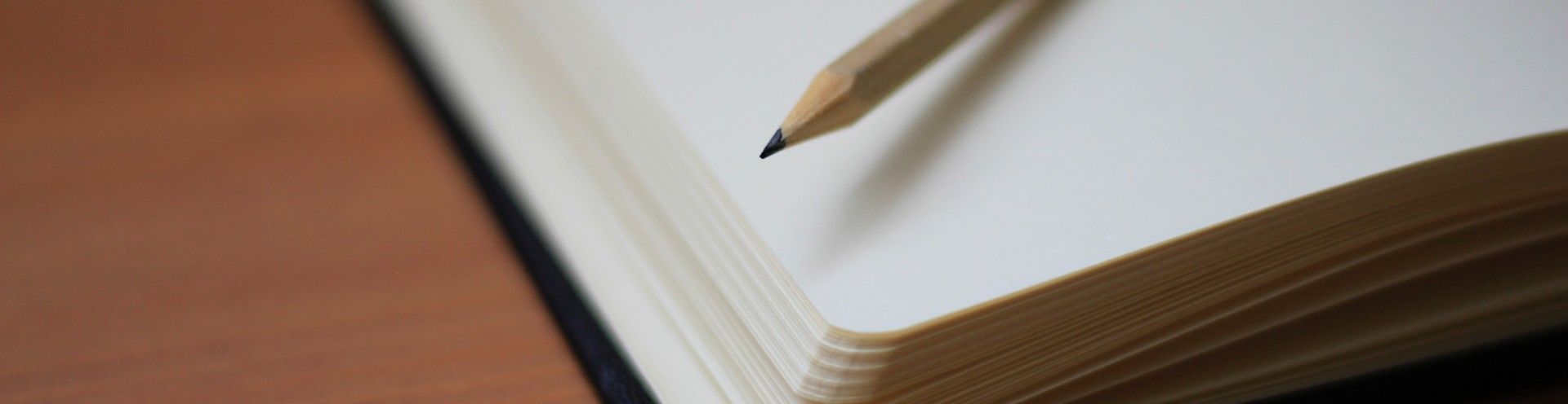 A pencil and a notebook on a desk.