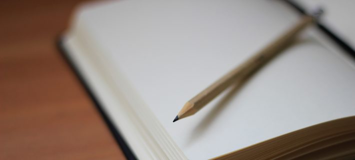 A pencil and a notebook on a desk.