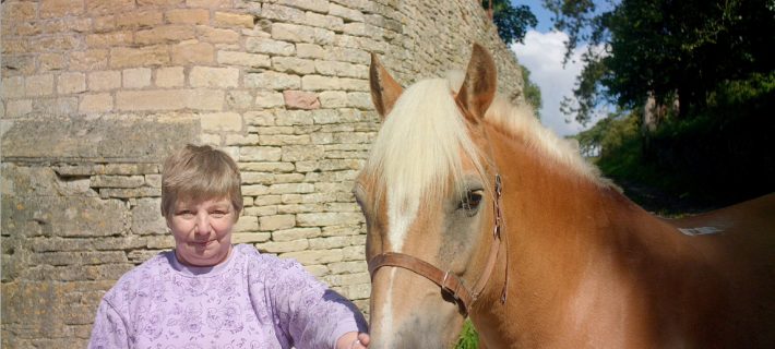 Roz standing next to beautiful horse and smiling at the camera.