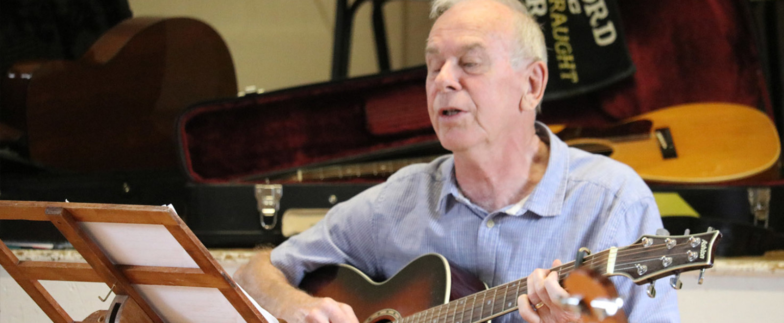 Elderly man playing guitar and singing.