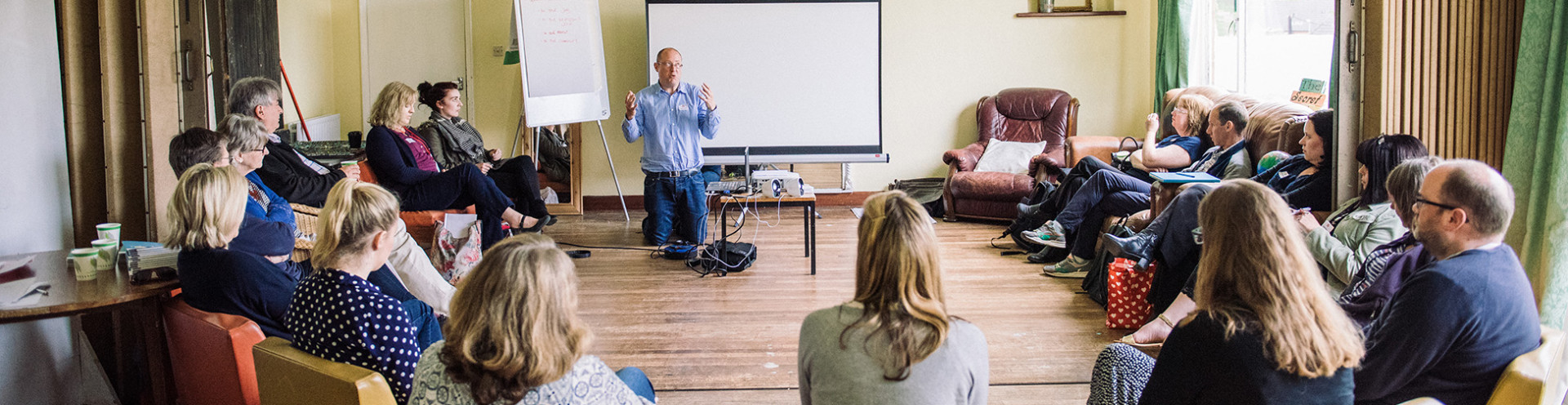 Community group members sitting in a meeting room and listening marketing tips and tricks for the community group