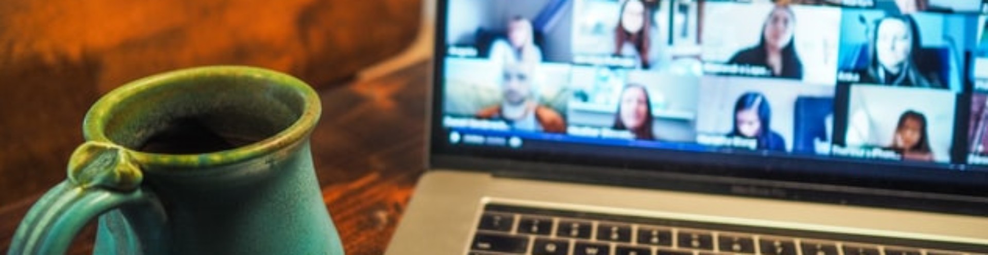 A photo of laptop with a zoom call on the right and a coffee cup on the left.