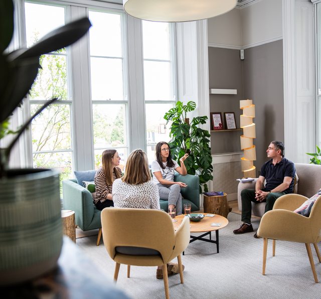 Photo of Barnwood staff talking while sitting down in the welcome area.