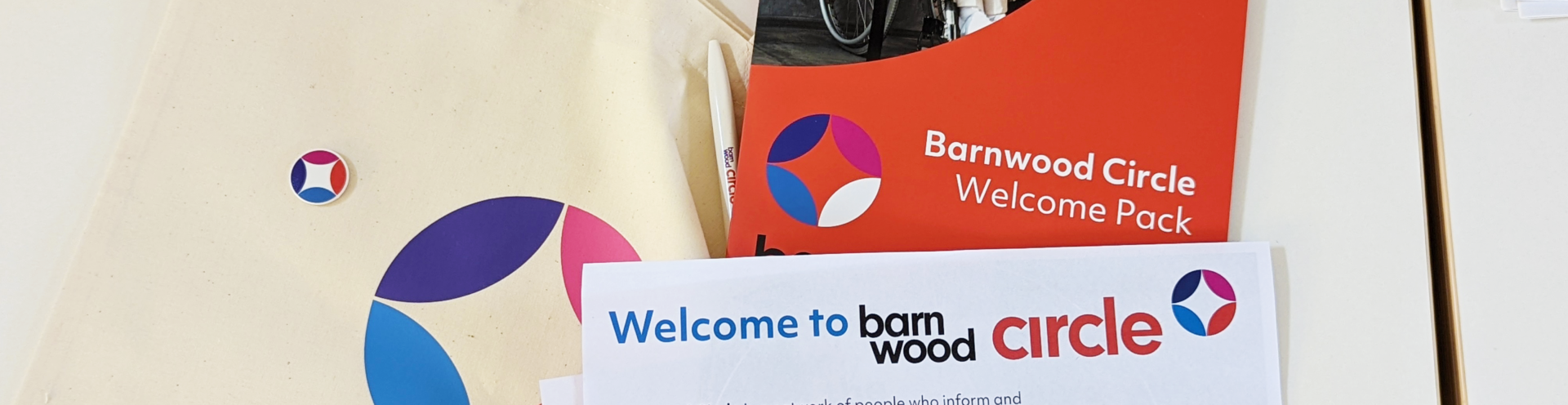 Photo of Barnwood Circle merchandise, a tote bag with the logo on, the welcome folder and a selection of inserts with details of the membership scheme
