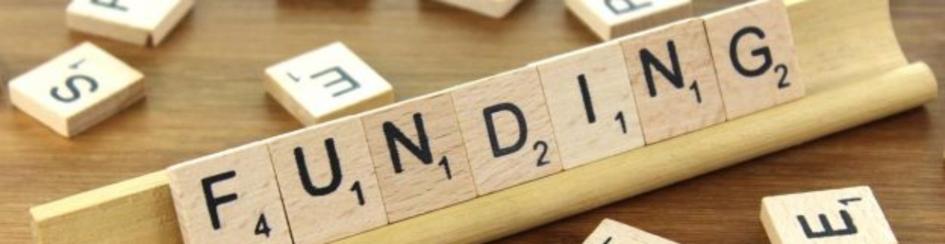 image shows scrabble tiles arranged to spell the word 'funding'