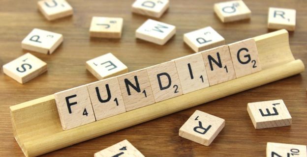 image shows scrabble tiles arranged to spell the word 'funding'