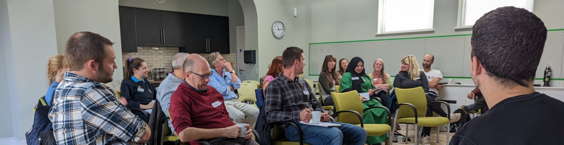 Photo of participants at a Barnwood Trust learning event. People are sat in rows of chairs listening to a presenter.