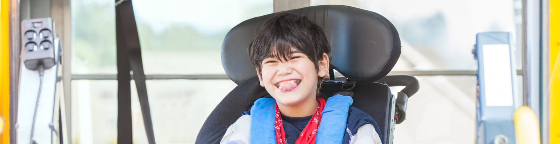 Photo of a boy smiling in an electric wheelchair, while on a bus