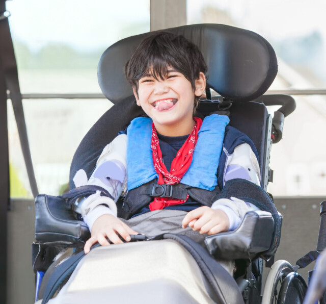 Photo of a boy smiling in an electric wheelchair, while on a bus