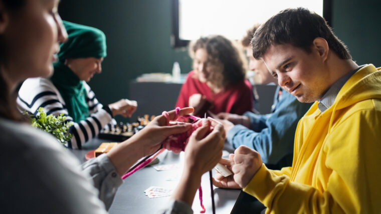 A photo of a group of people playing games around a table in a community centre.