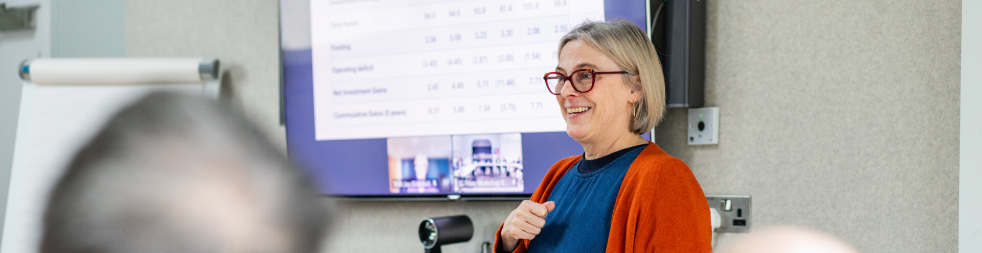Nicola Mosley leading a meeting, smiling and standing in front of a screen