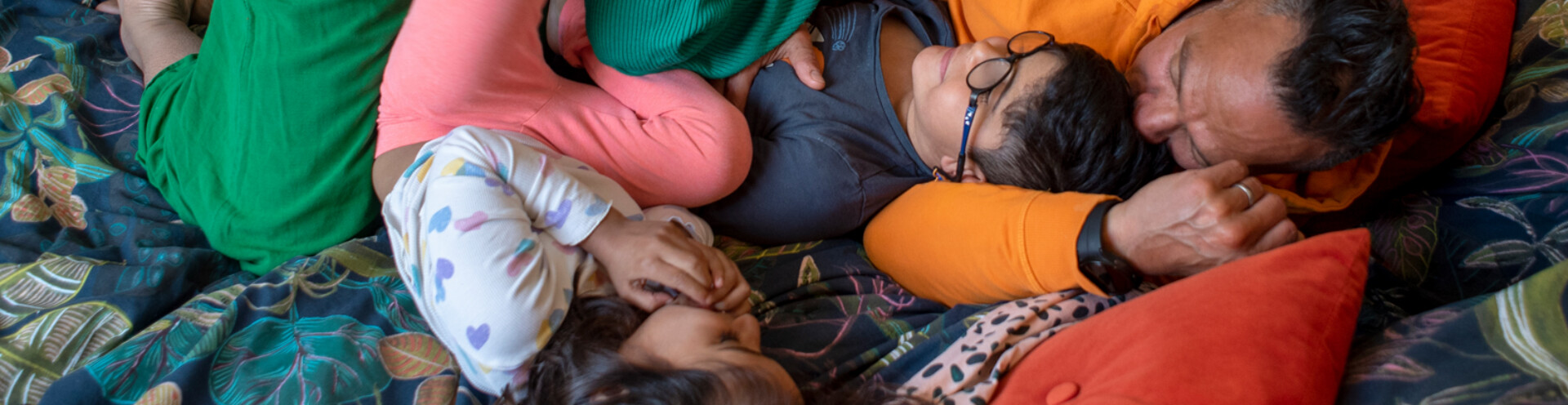 A happy family cuddling on a bed.
