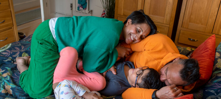 A happy family cuddling on a bed.